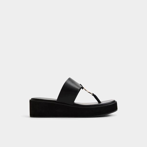A single black platform thong sandal with a wide strap and a small gold-tone metal accent, shown in profile against a light gray background.